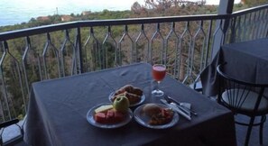 A table with food and a drink on a balcony overlooking a scenic view. - Hotel Due Gemelli (Riomaggiore)