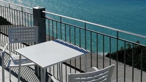 Una terraza con mesa y sillas con vista al mar azul y transparente.