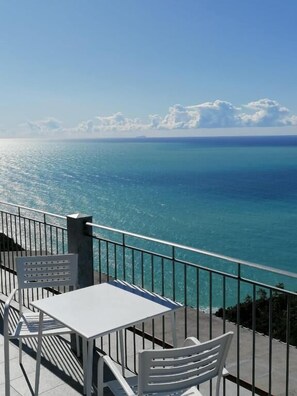 A terrace with a table and chairs overlooking a clear blue sea. - Hotel Due Gemelli (Riomaggiore)
