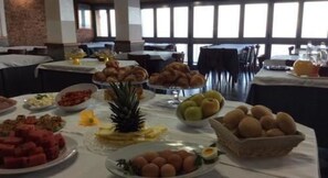 A buffet table with various food items including fruits, pastries, and eggs.
