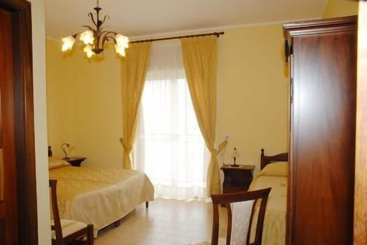 A bedroom with a bed, a chair, a nightstand, and a wardrobe.