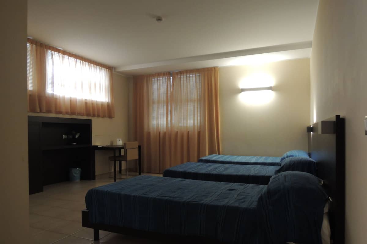 A hotel room with two beds, a desk, and a chair.