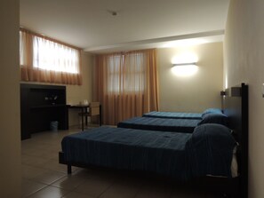 Ein Hotelzimmer mit zwei Betten, einem Schreibtisch und einem Stuhl.