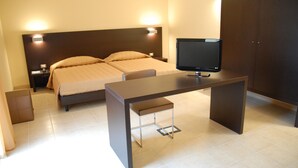 Hotellihuone, jossa on sänky, työpöytä, tuoli, televisio ja vaatekaappi.