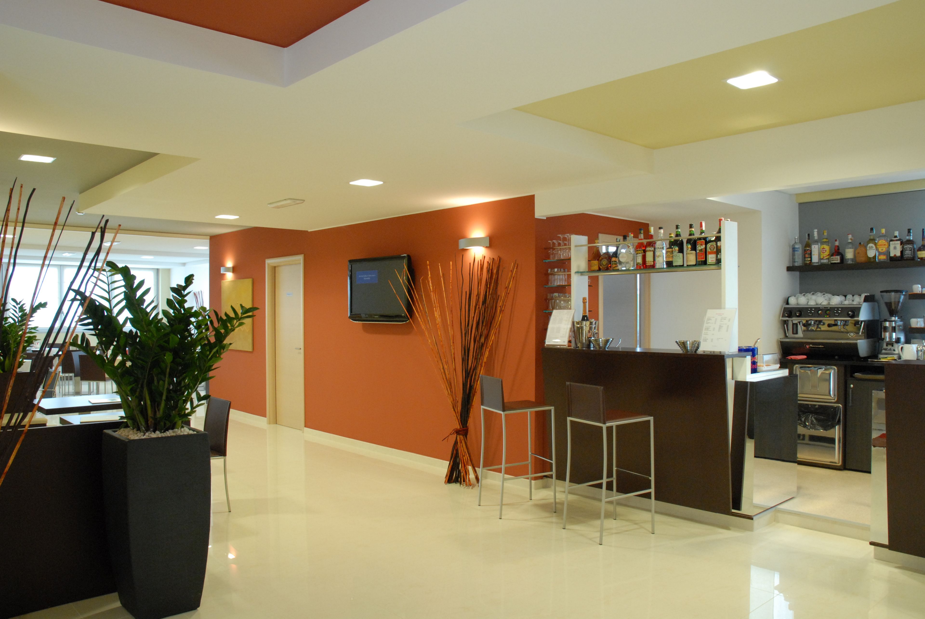 A modern hotel lobby with a reception desk, bar area, and seating.