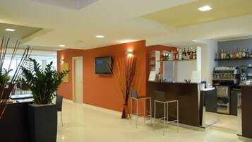 A modern hotel lobby with a reception desk, bar area, and seating.