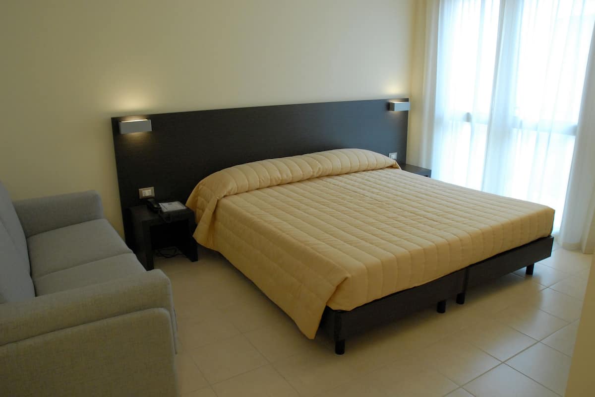 A modern hotel room with a bed, bedside table, and a chair.