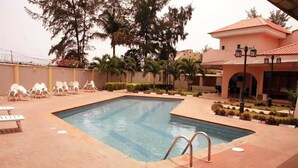 A swimming pool with lounge chairs and a covered area with a lamp post. - Solitude Hotel Victoria Island (Lagos)