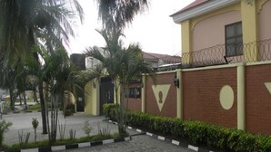A building with a yellow facade, a brick lower section, and a barred balcony. - Solitude Hotel Victoria Island (Lagos)