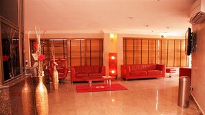 A spacious living room with a red sofa set, a coffee table, and decorative vases. - Solitude Hotel Victoria Island (Lagos)