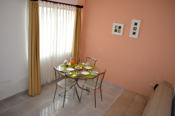 A dining area with a round glass table, four chairs, and a beige sofa.
