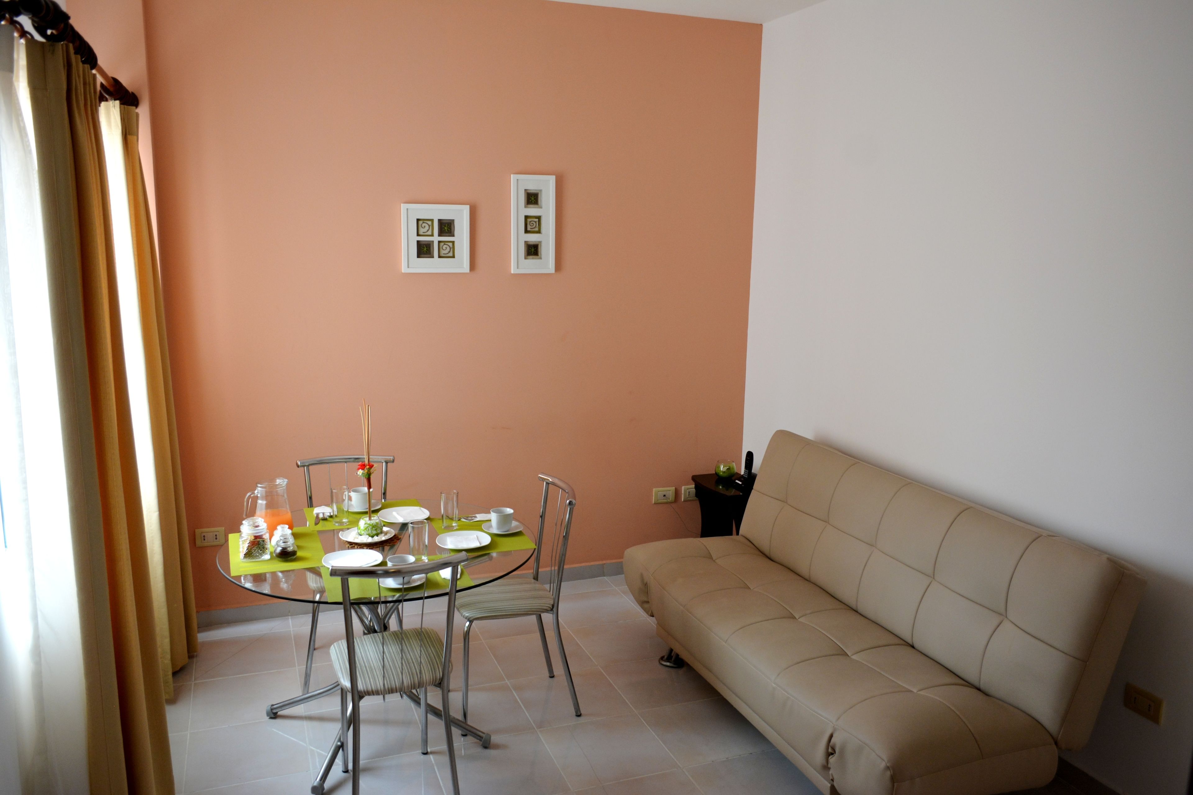Un comedor con una mesa redonda, sillas y un sofá. Hay dos cuadros en la pared.
