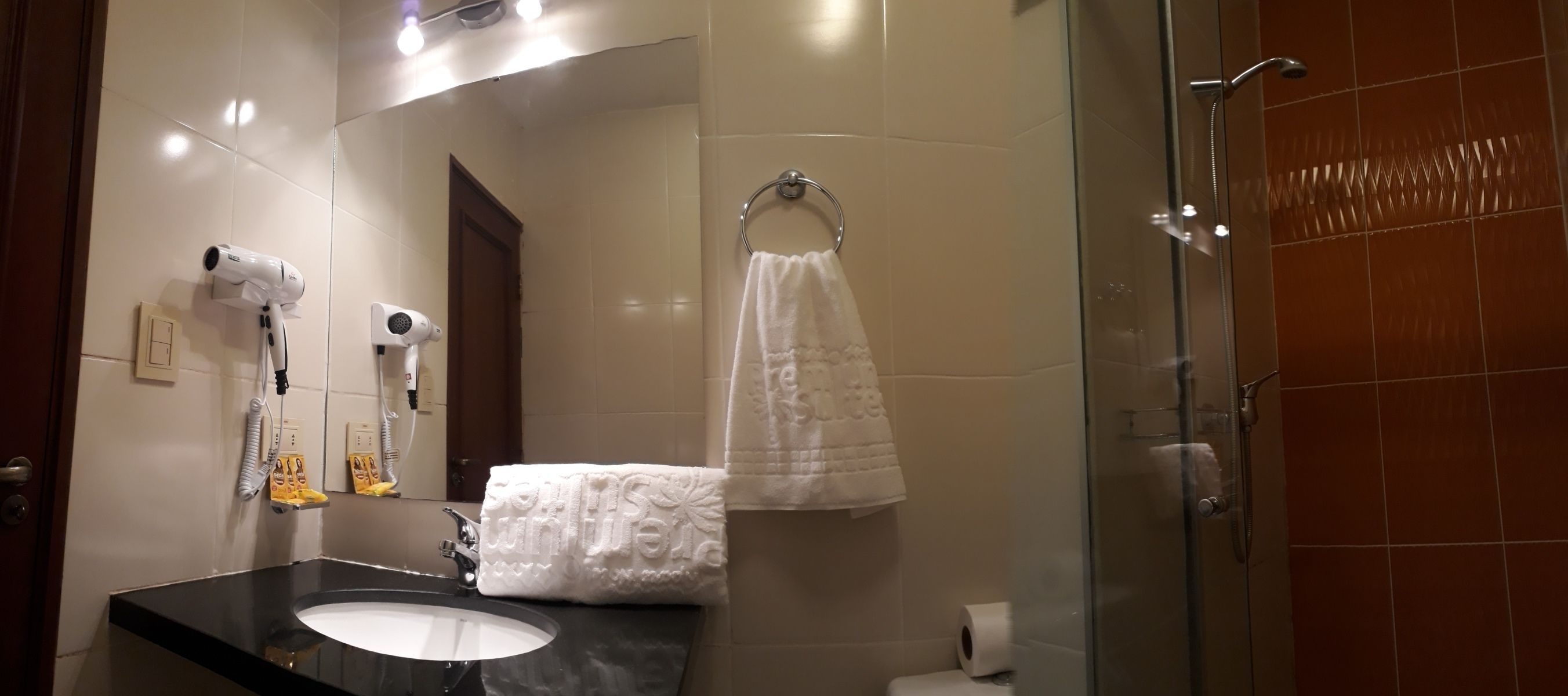 A bathroom with a black sink, white towel, and a glass shower enclosure.