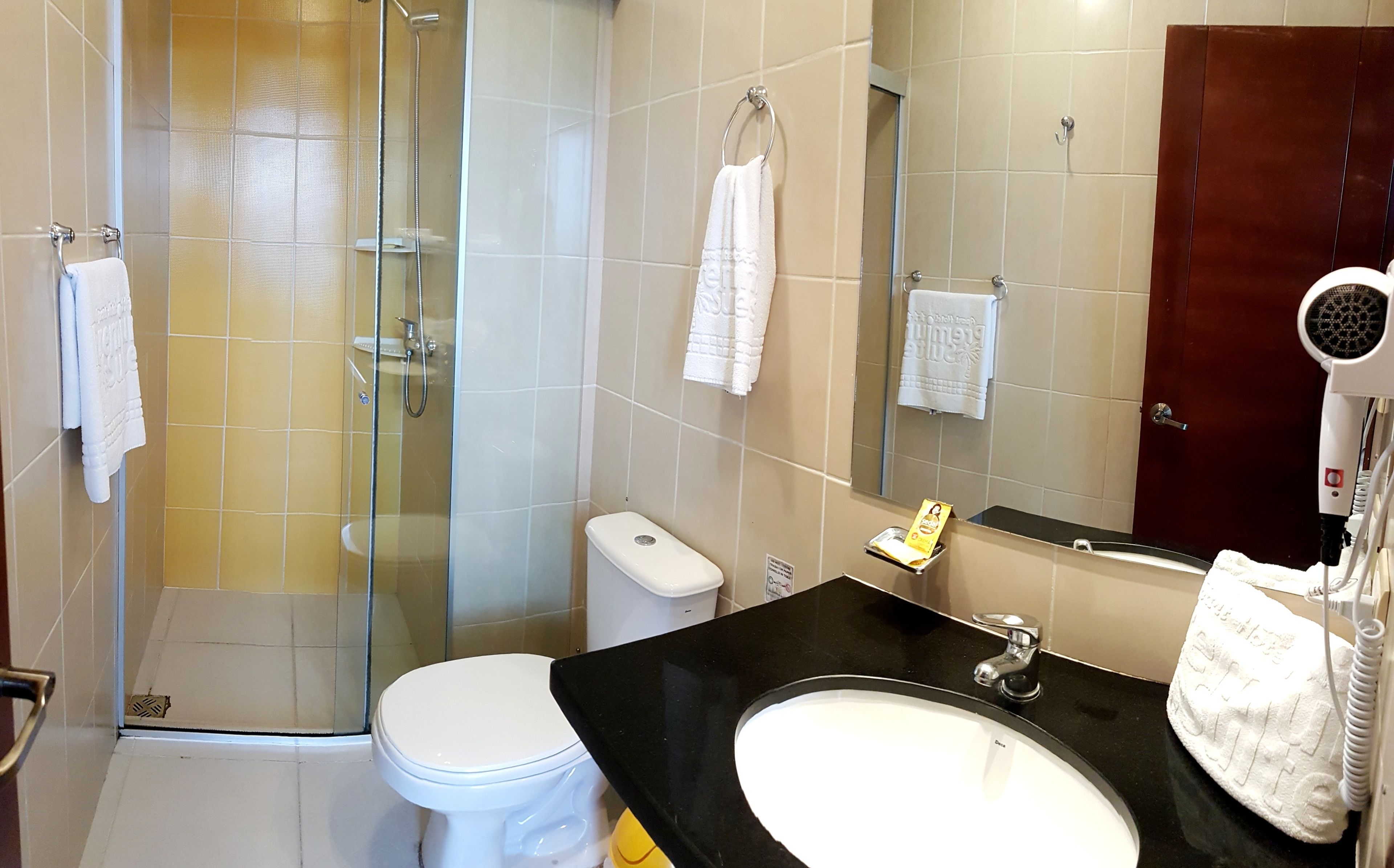 Un baño con ducha envuelta en vidrio, inodoro, lavamanos y espejo.