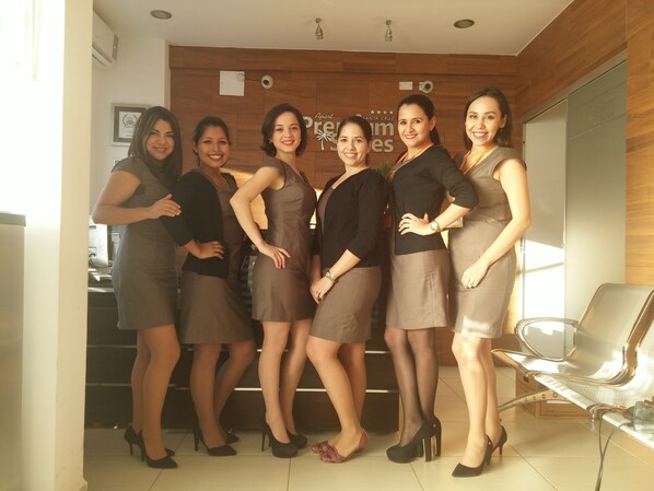 Un grupo de mujeres de pie en un interior moderno con paneles de madera y una recepción.