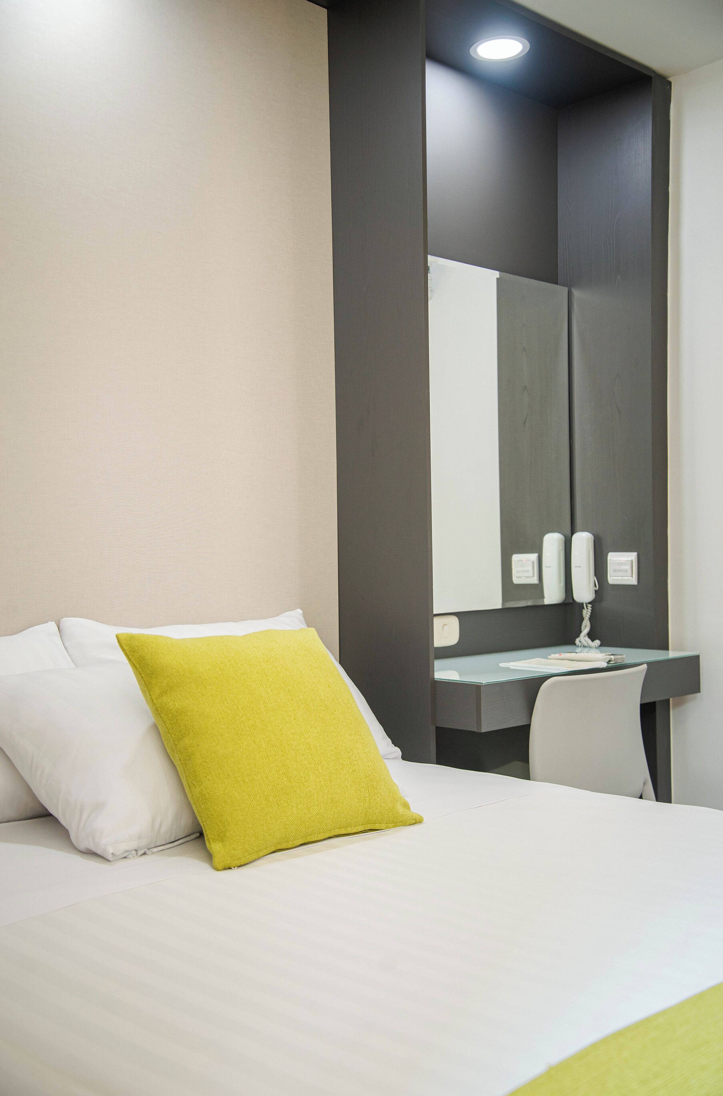 Una habitación de hotel con una cama, un escritorio y un espejo.