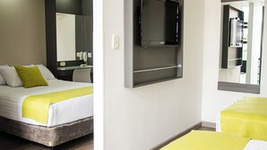 A hotel room with two beds, a desk, a mirror, and a television.