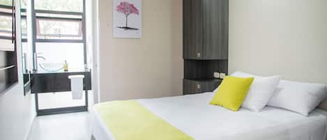 Una habitación de hotel moderna con una cama, una mesita de noche, un espejo y una ventana con vistas.