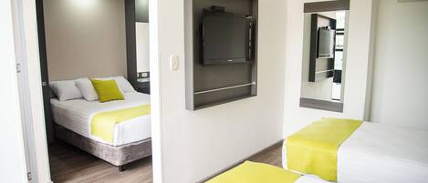 A hotel room with two beds, a flat-screen TV mounted on the wall, and a mirror above the bed.