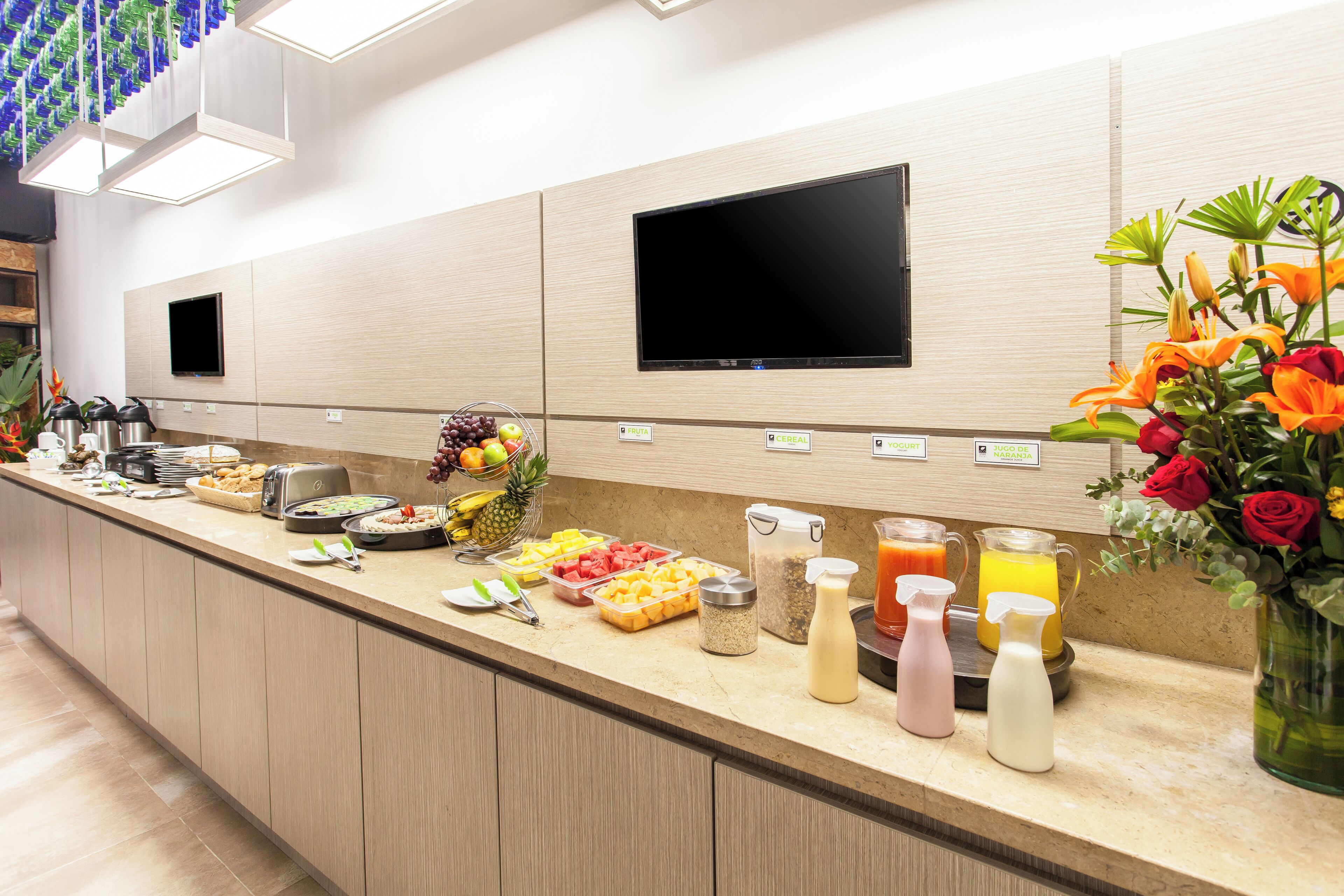 A breakfast bar with various food items, a television, and a vase of flowers.