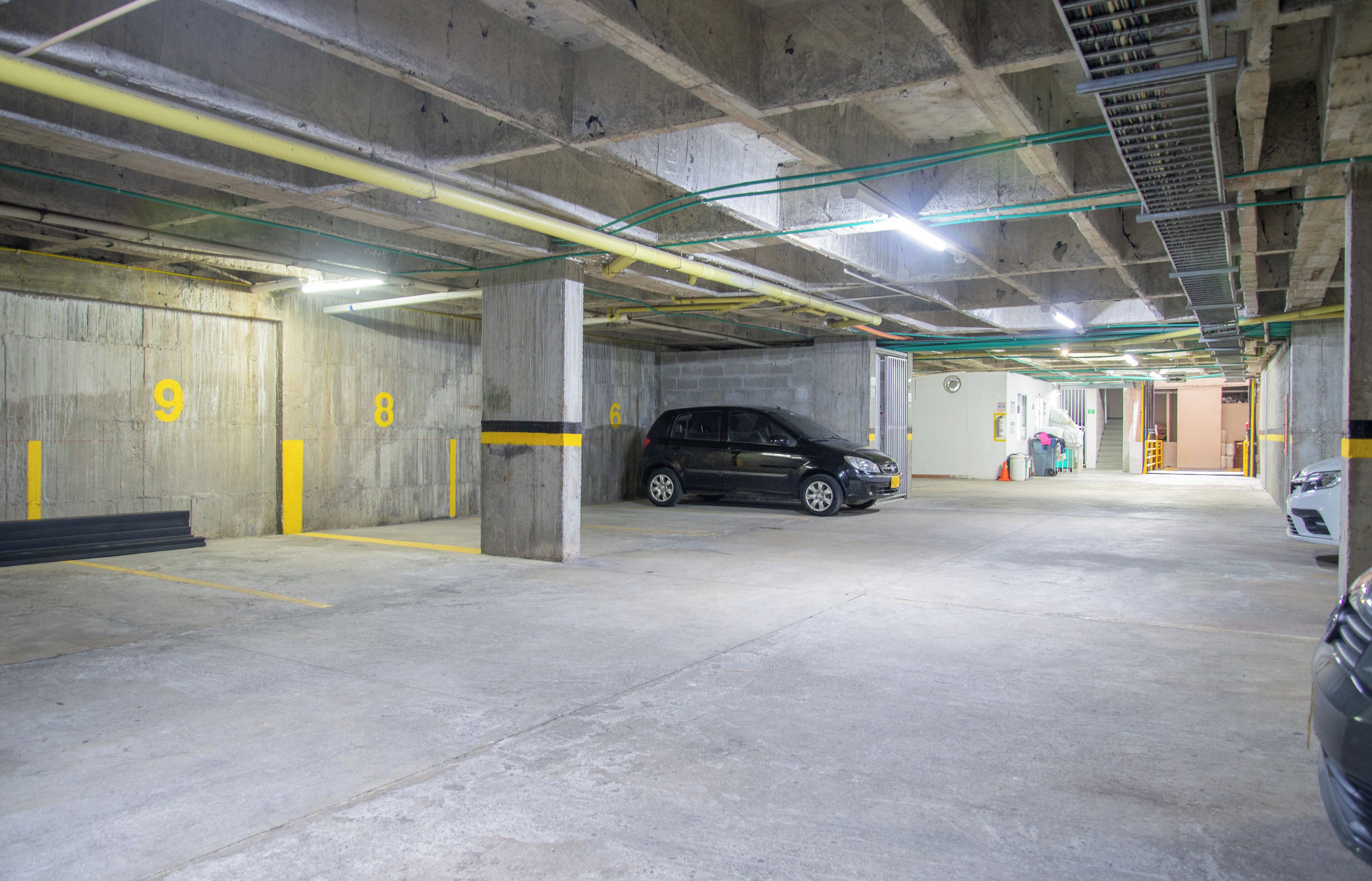 Un estacionamiento de varios niveles con paredes de hormigón y líneas amarillas que delimitan las plazas.
