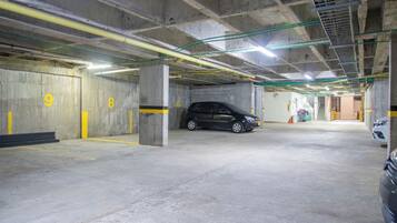 Un estacionamiento de varios niveles con paredes de hormigón y líneas amarillas que delimitan las plazas.