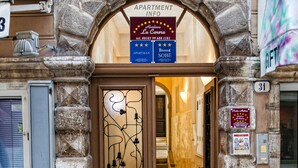 An entrance to an apartment building with a stone archway, a sign indicating 'Apartment Info' and 'La Casa de la Carnera', and a staircase leading inside. - Residence La Carera (Rovinj)