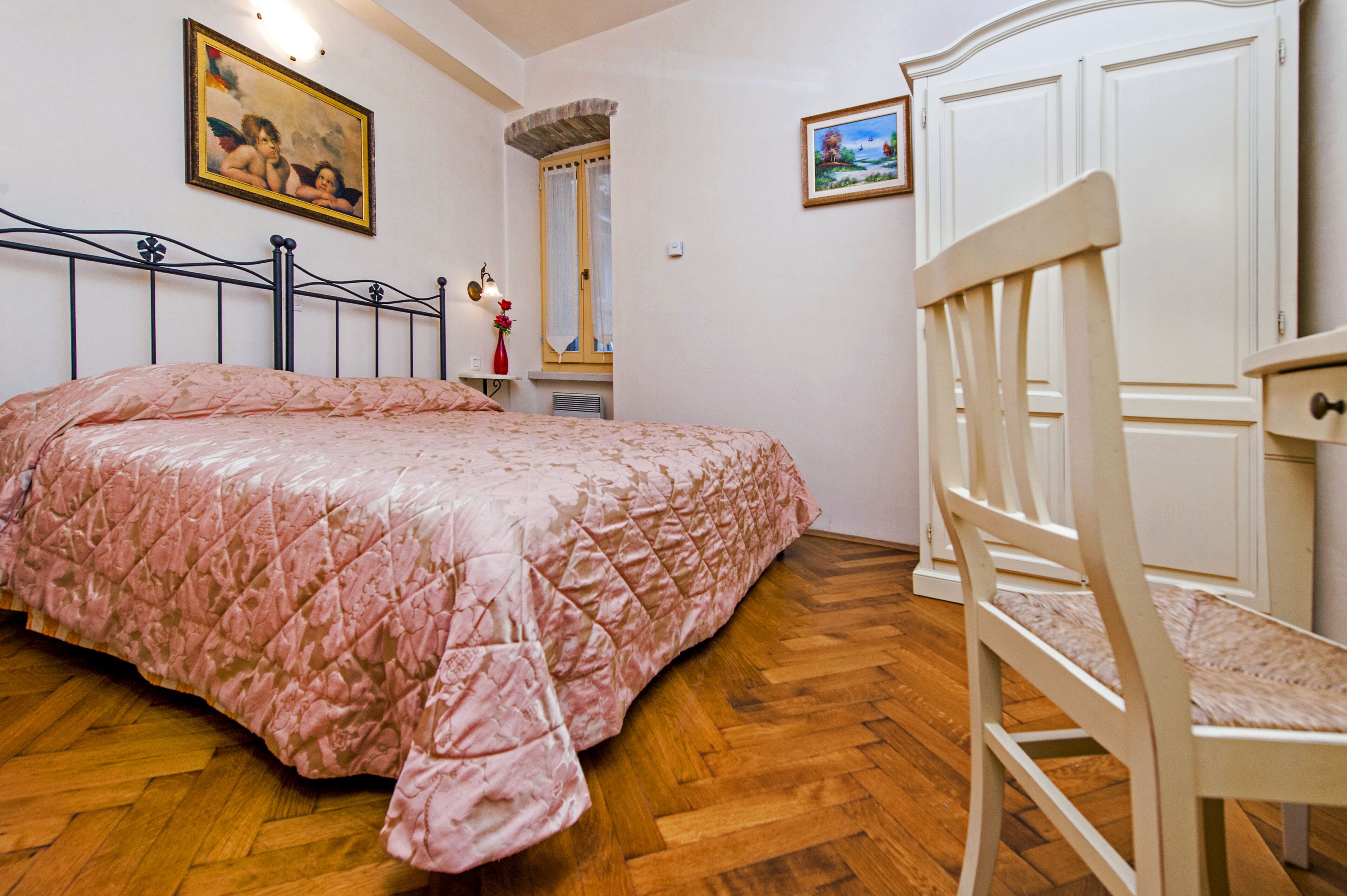 Une chambre à coucher avec un lit, une chaise, une armoire et un tableau au mur.