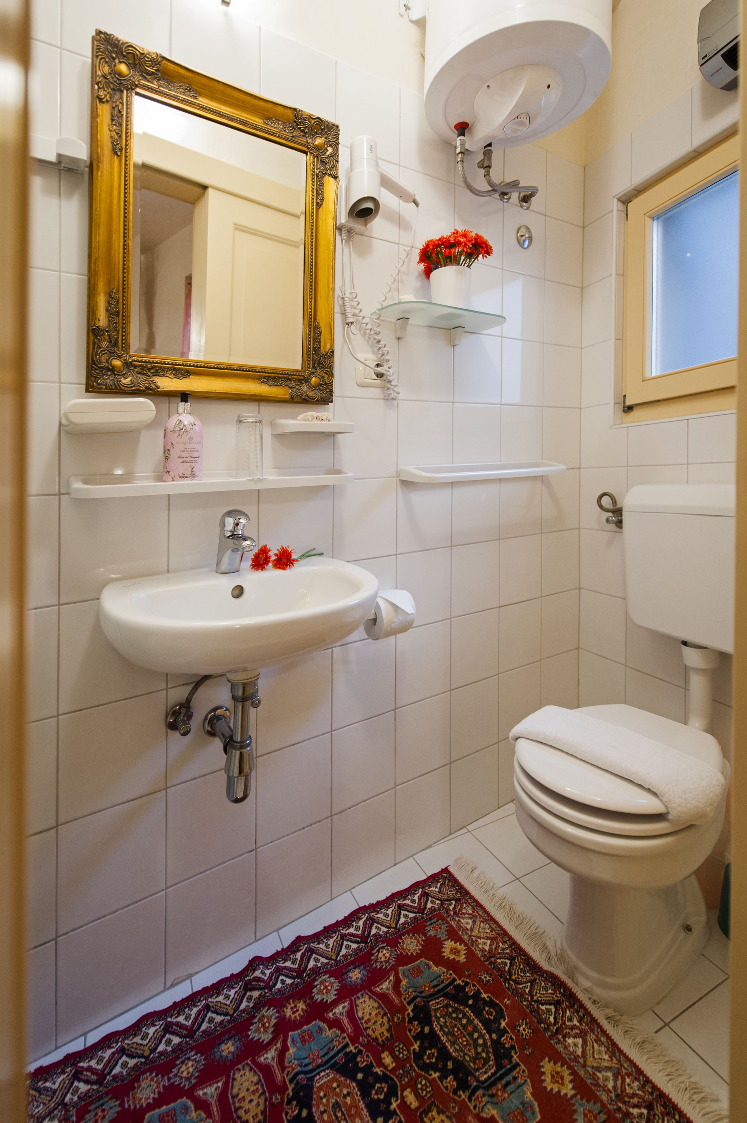Un baño con lavamanos blanco, inodoro, espejo y cabezal de ducha.