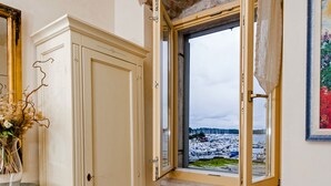 A room with a wooden herringbone floor, a white wardrobe, a window with a view of a marina, and a radiator below the window. - Residence La Carera (Rovinj)
