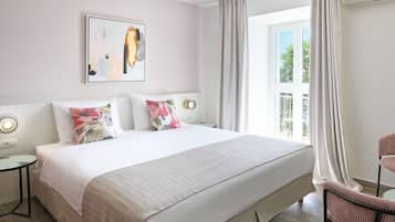 A hotel room with a large bed, a bedside table, a chair, a window with curtains, and a wall-mounted air conditioner.