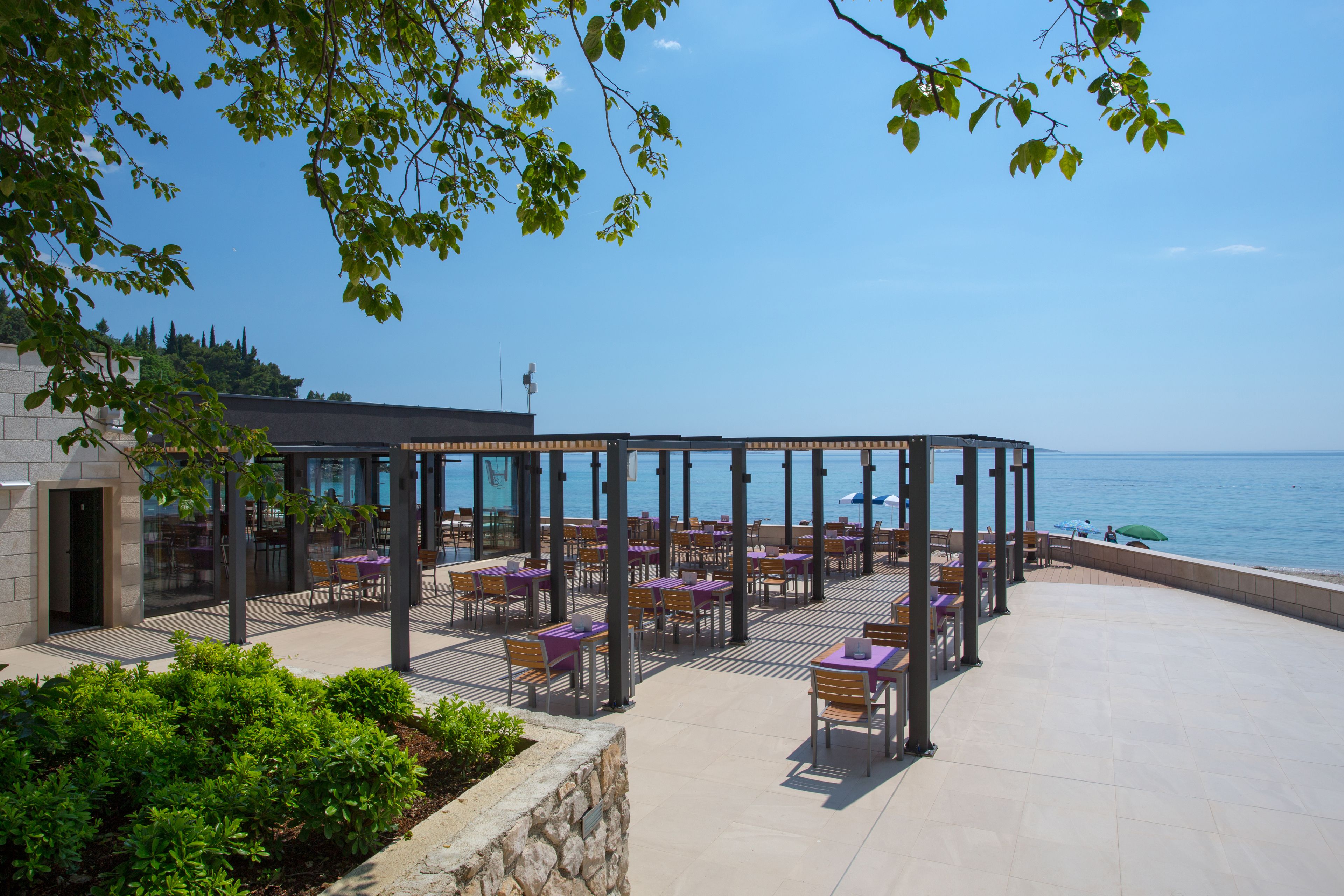 An outdoor seating area with tables and chairs, overlooking a body of water.