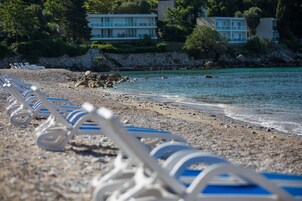 Una playa con hileras de sillas de playa blancas y un litoral rocoso.