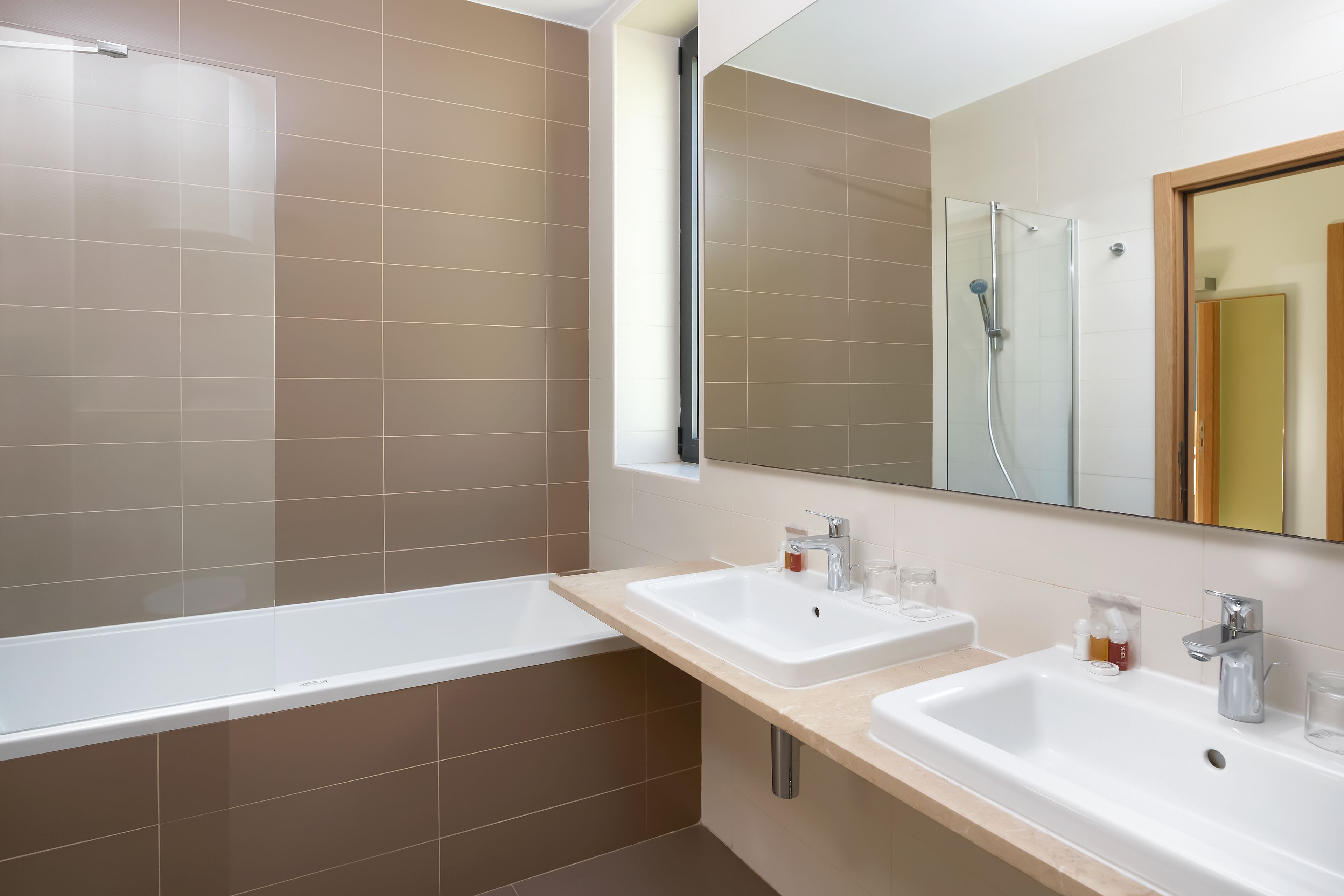 Un baño moderno con dos lavamanos, una ducha y un espejo grande.