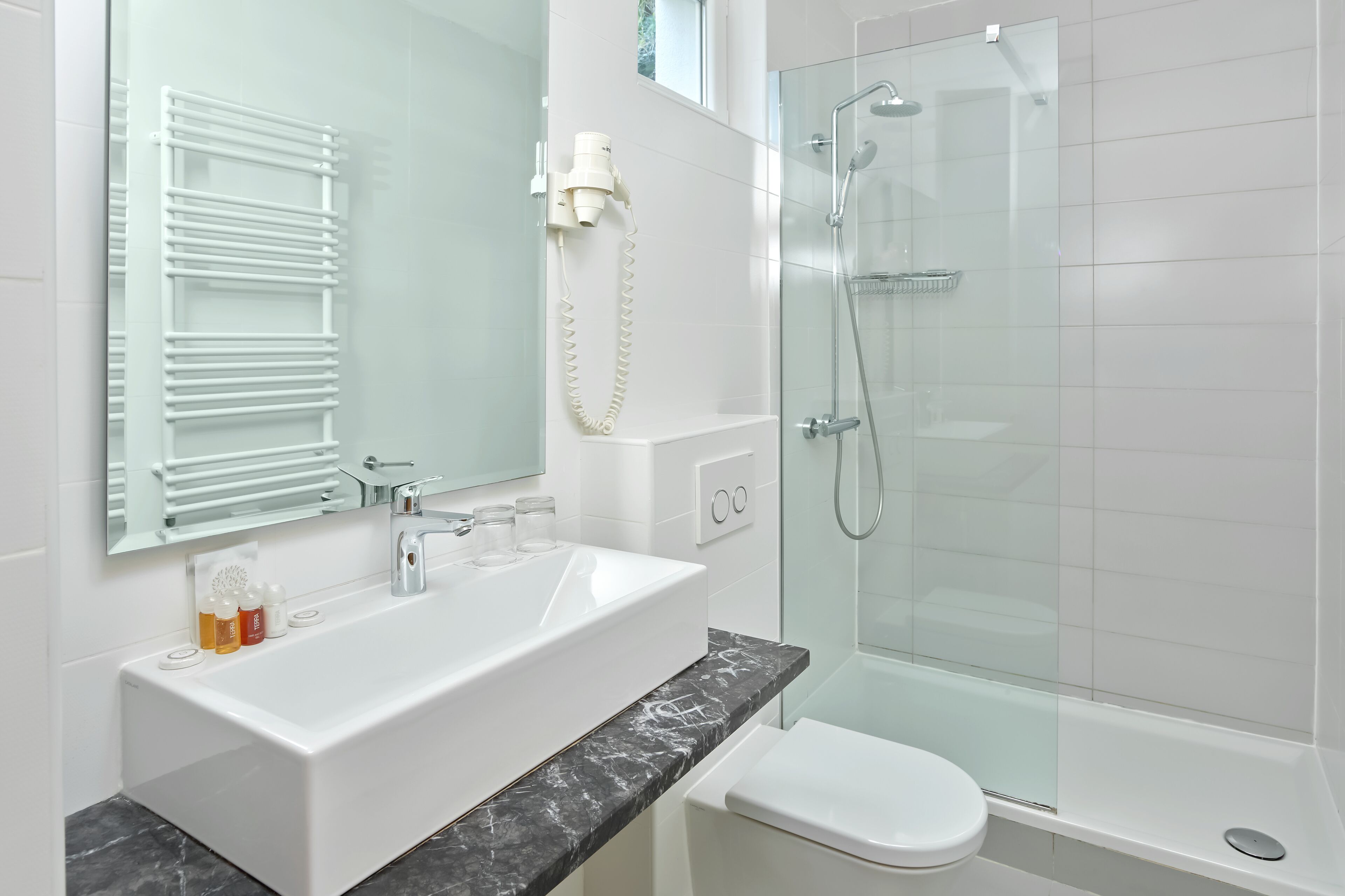 A modern bathroom with a white sink, a glass shower enclosure, and a toilet.