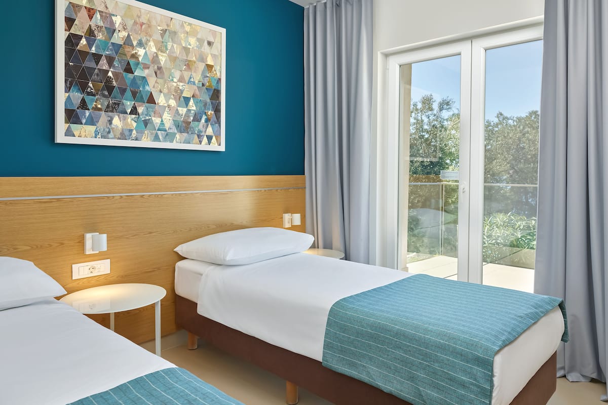 Une chambre d’hôtel avec deux lits, une tête de lit en bois, une œuvre d’art murale et un balcon avec des rideaux.