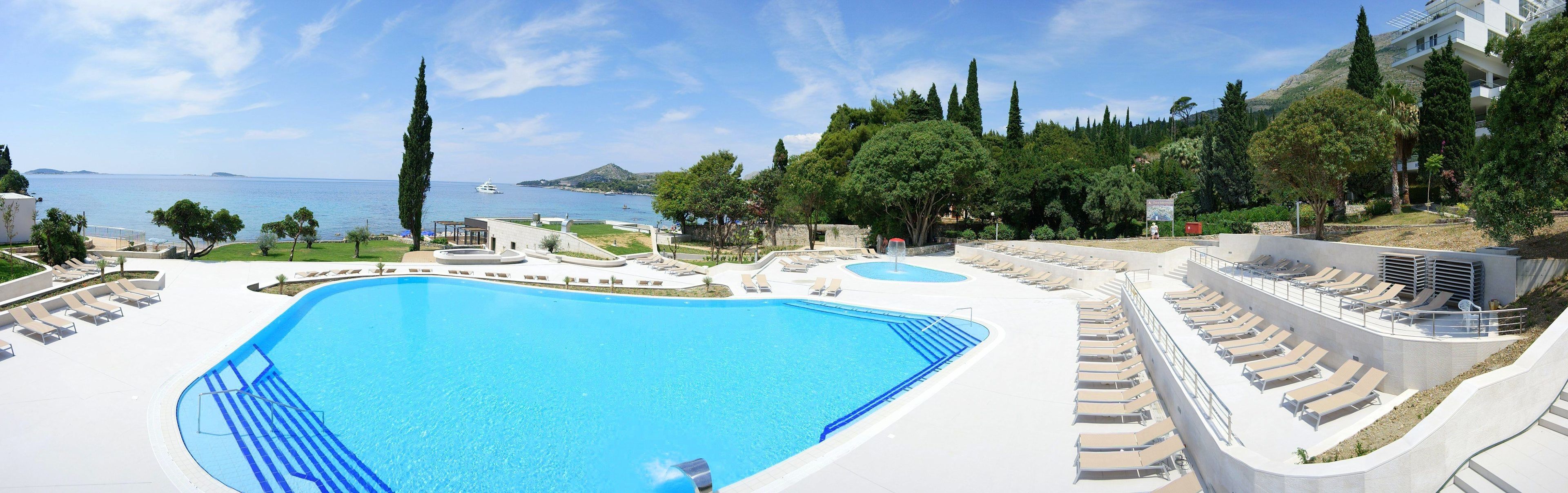 Une grande piscine avec des chaises longues et vue sur la mer.