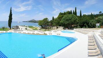 Una gran piscina con tumbonas y vistas al mar.