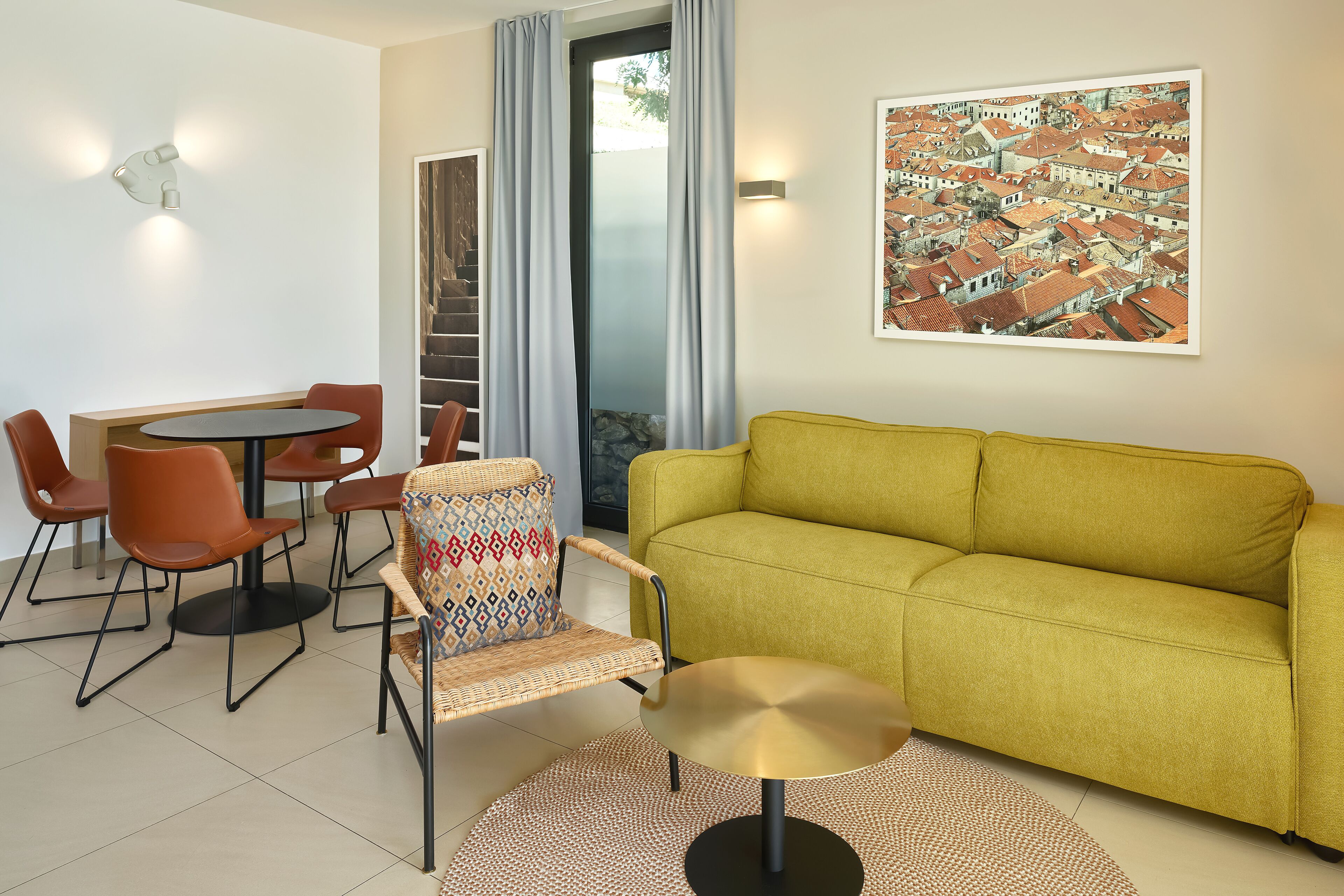 Una sala de estar moderna con un sofá amarillo, una mesa de comedor con sillas y un cuadro grande en la pared.