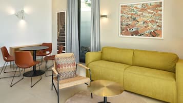 Una sala de estar moderna con un sofá amarillo, una mesa de comedor con sillas y un cuadro grande en la pared.