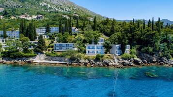 Un hotel costero con edificios de varios pisos, una costa rocosa y aguas azul turquesa.