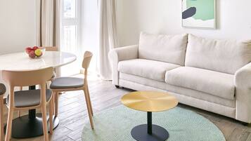 Una sala de estar con un sofá, una mesa redonda de centro y una mesa de comedor con sillas.