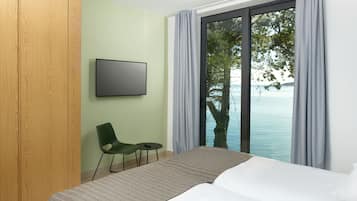 Una habitación de hotel con cama, televisor, sillón y vista al mar.
