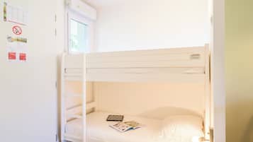 Un lit superposé avec une fenêtre, un climatiseur fixé au mur et un luminaire.