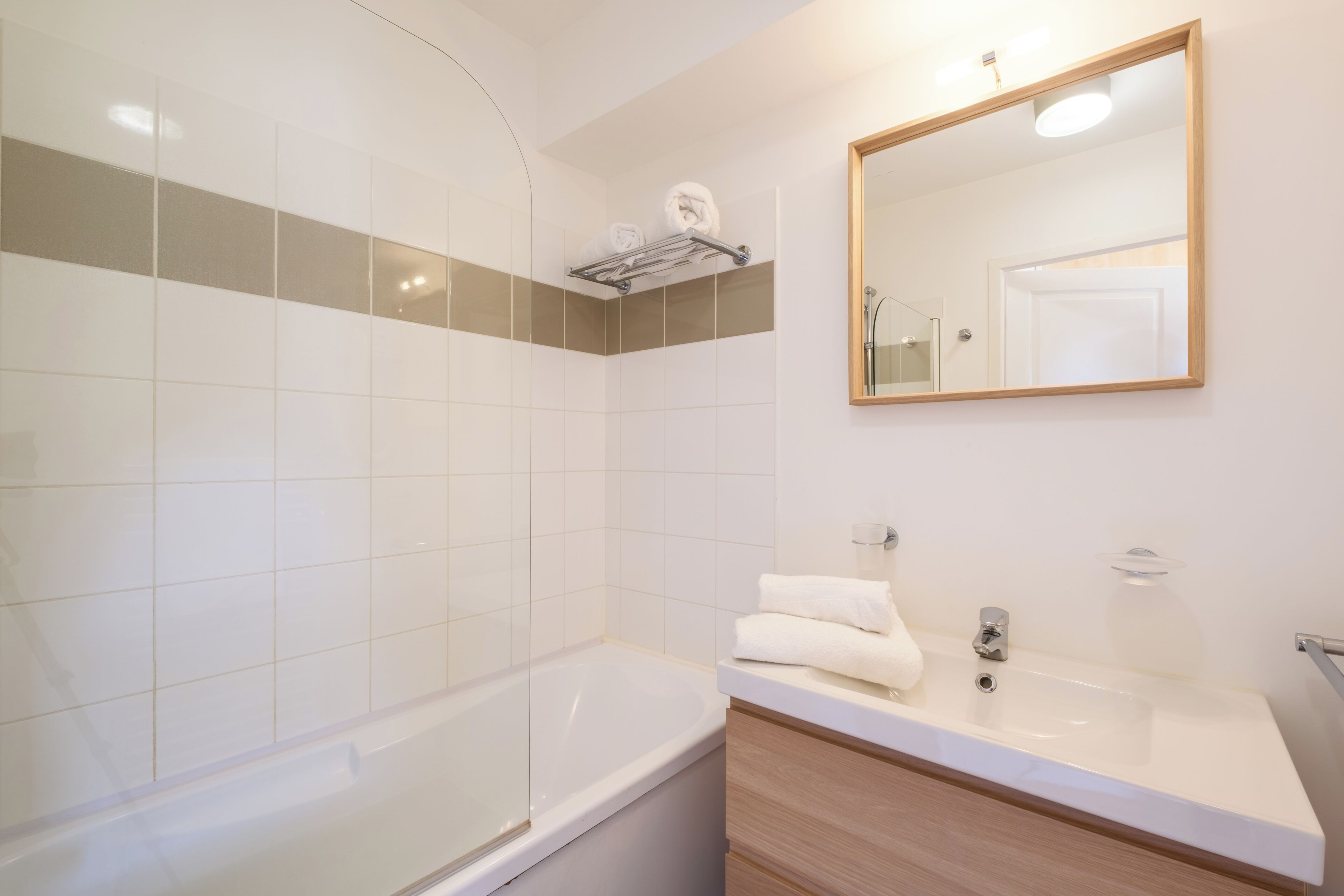 A modern bathroom with a bathtub, a sink, and a mirror.