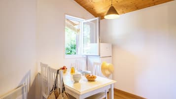 Une pièce avec une table blanche, une fenêtre, un radiateur et un luminaire suspendu.