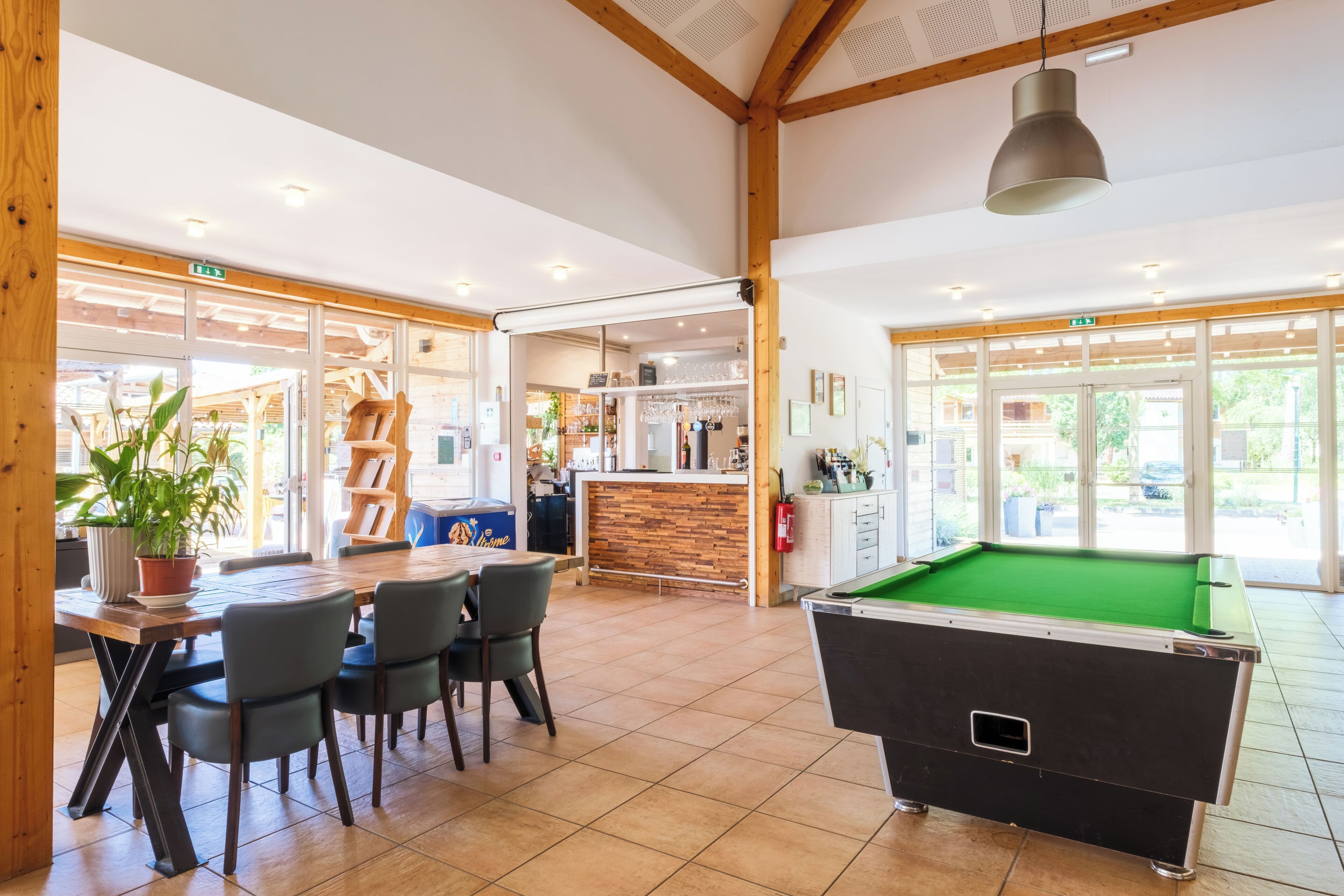 A billiards table, a pool table, and a bar area with a wooden counter and shelves.