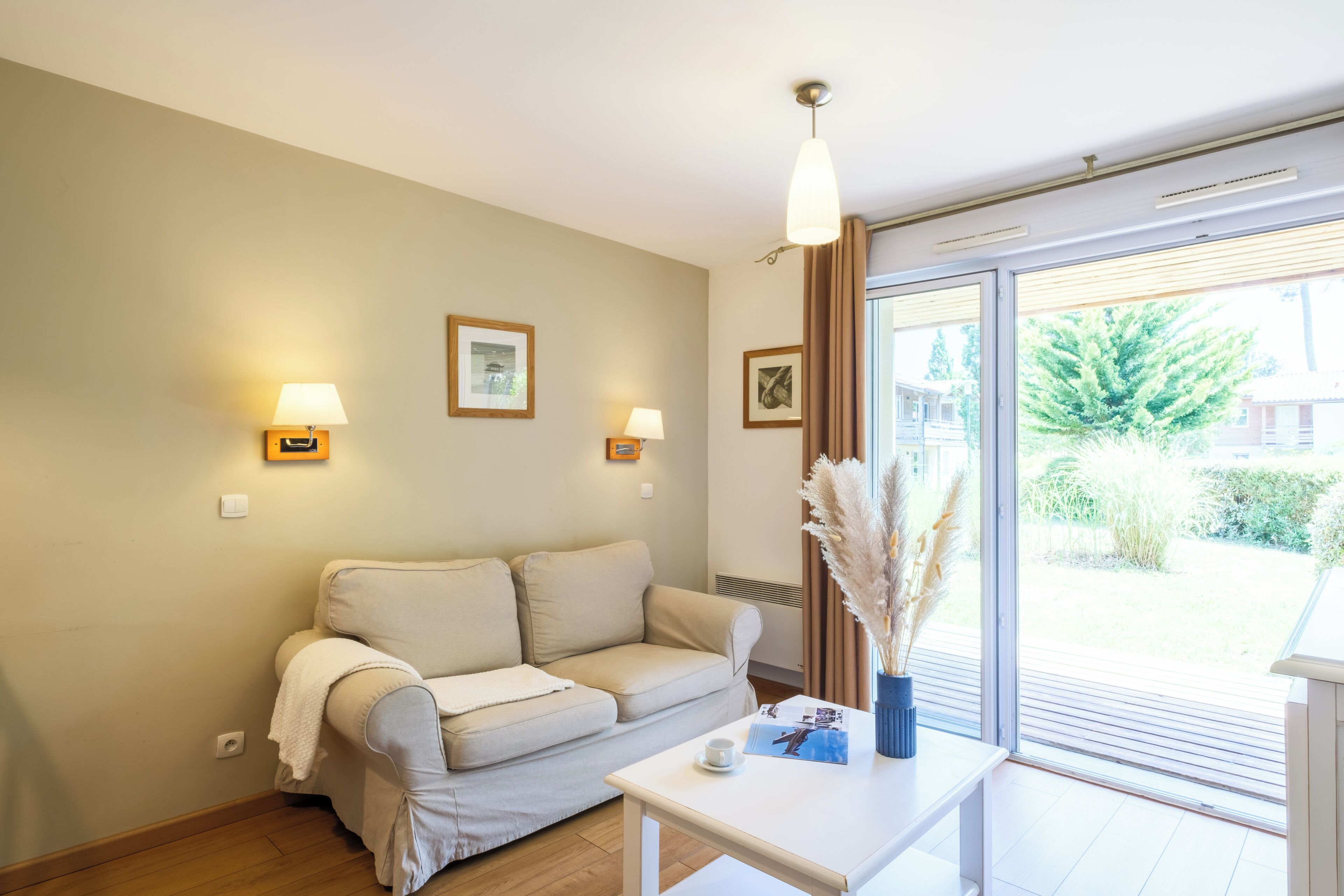 A modern living room with a sofa, a coffee table, and two wall-mounted lamps.
