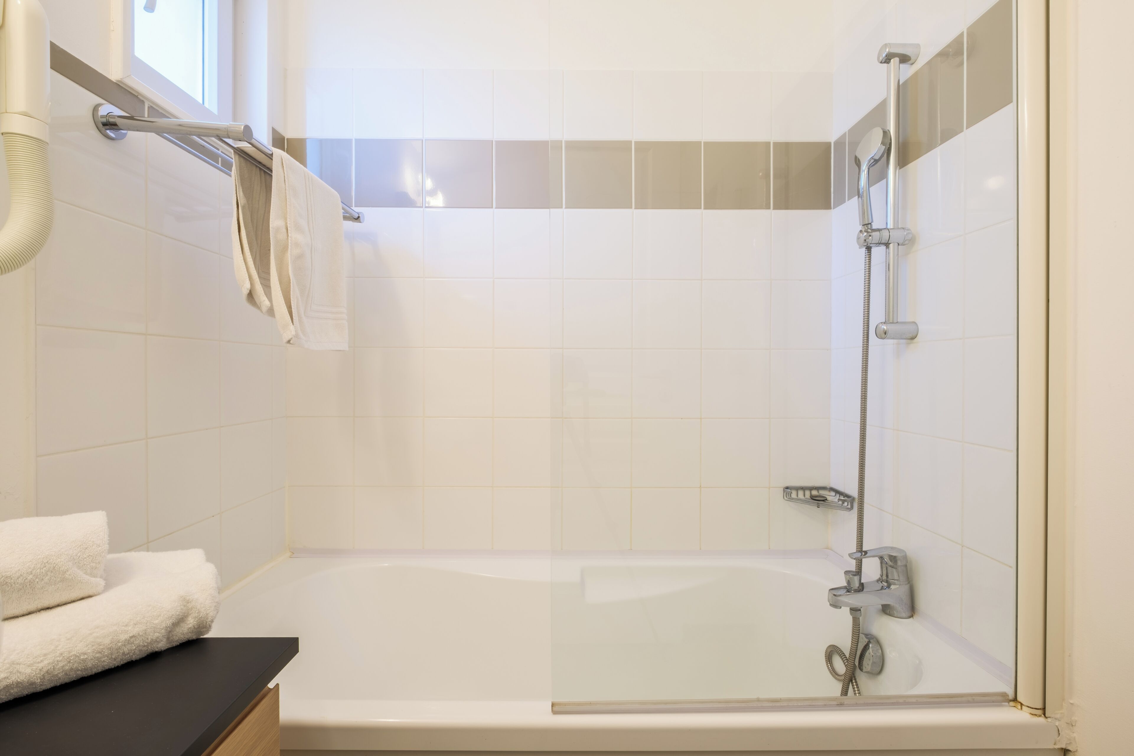 A bathroom with a bathtub, a towel rack, and a shower head.