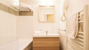Une salle de bain moderne avec une baignoire, un meuble-lavabo en bois, un miroir et un porte-serviettes.